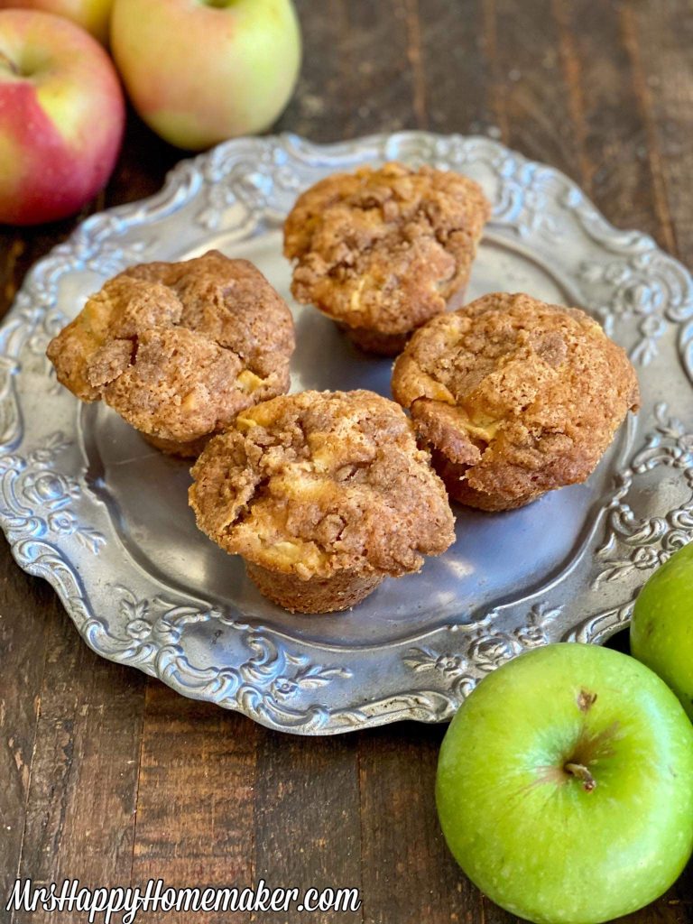 Apple pie muffins on a silver plate surrounded by apples