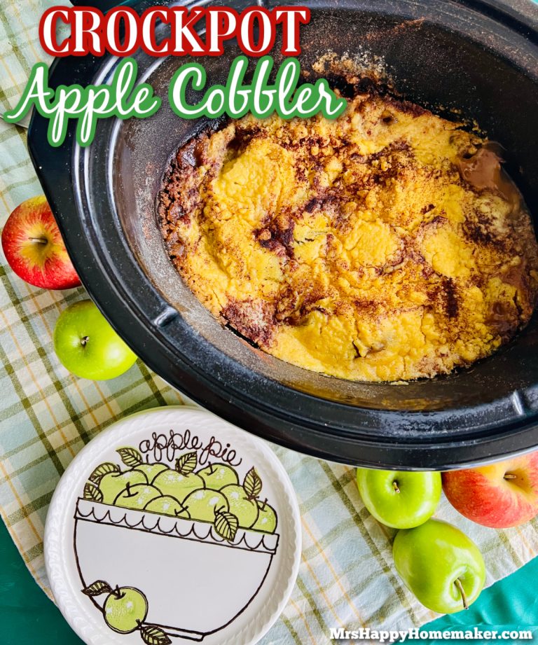 Apple cobbler in a black crockpot with an ‘apple pie’ design plate beside of it